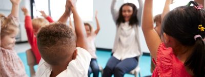 A class of infant school children sitting on chairs in a circle in the classroom